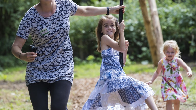 A girl sits on a zip wire which is pulled by a woman next to her